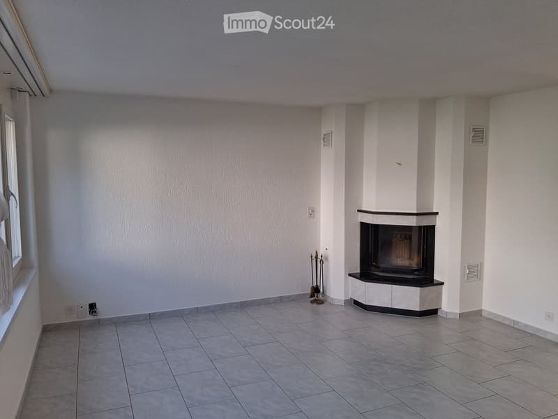 Empty room with tiled floor, white walls, and a fireplace with a black surround. A window is visible on the left side.