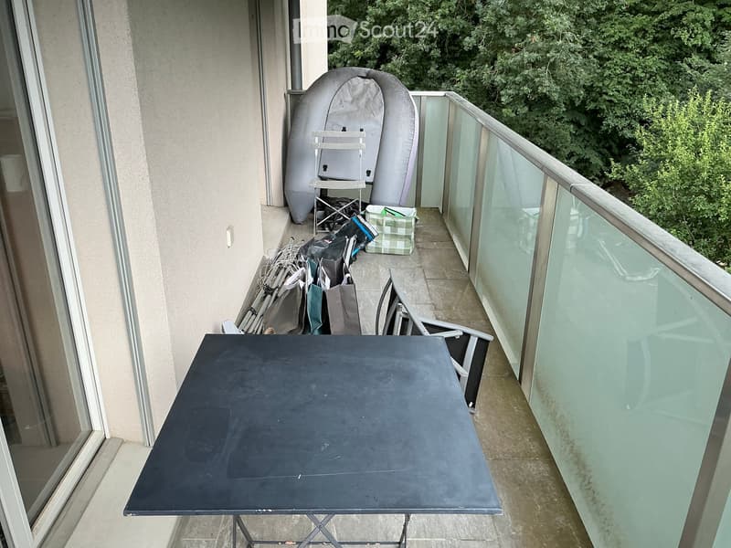 Balcony with a black folding table, a folding chair, and a large inflatable boat in the corner.