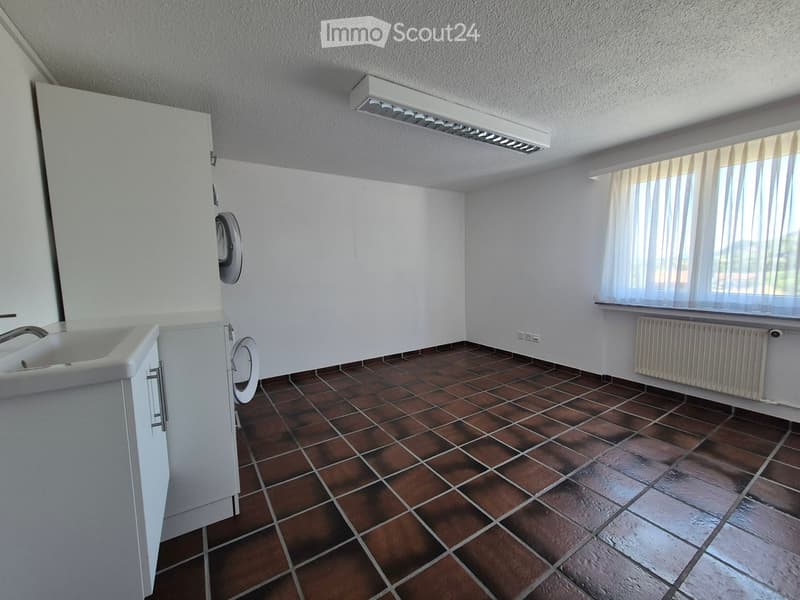 Bathroom with brown tiled floor, white sink, radiator, and window with blinds.