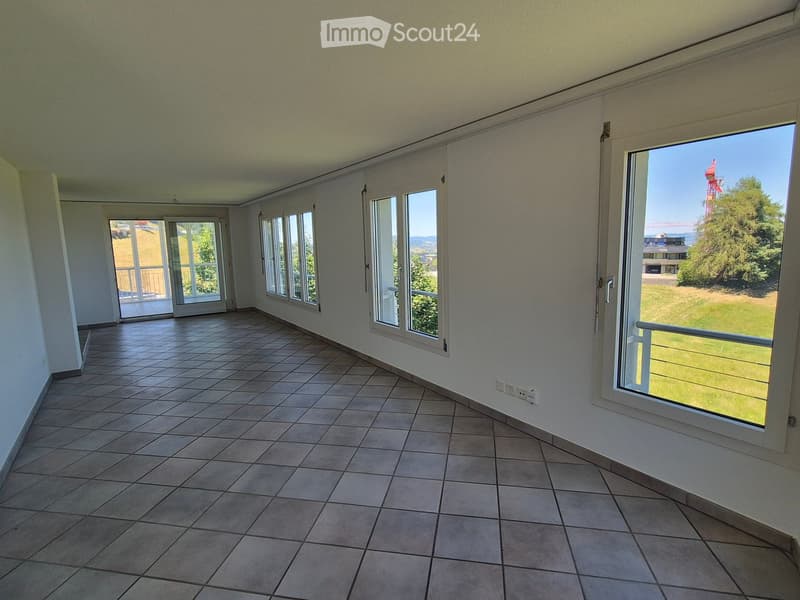 Empty room with tiled floor, large windows, and sliding doors leading to a balcony.