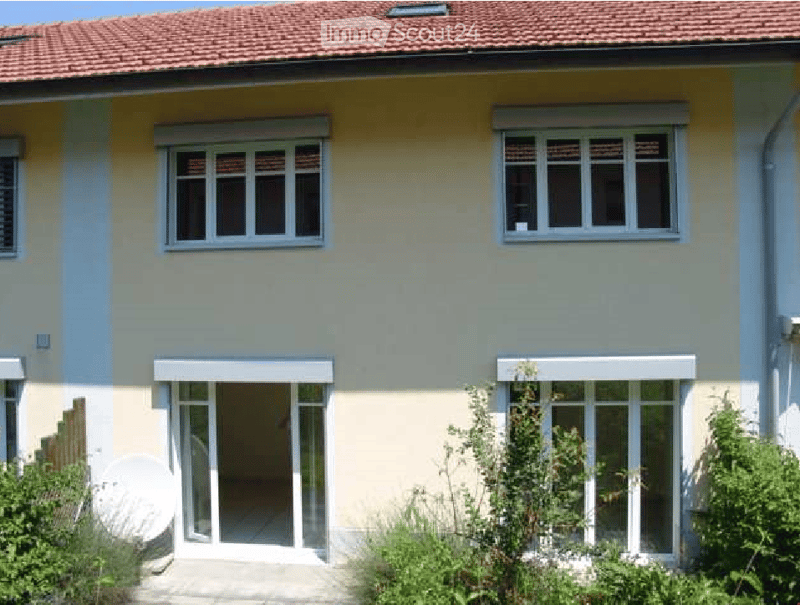 Two-story house with light yellow and blue exterior, multiple windows, and a satellite dish on the roof.