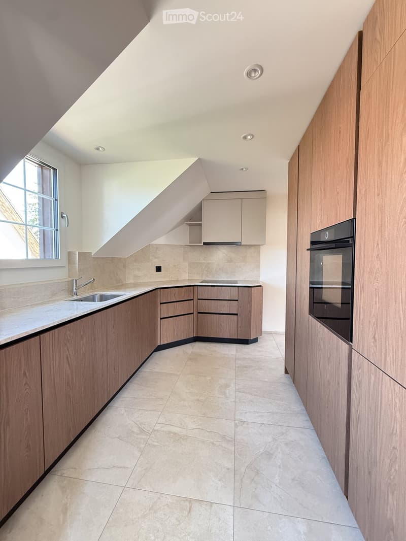 Modern kitchen with wooden cabinets, marble countertops, and a built-in oven. Features a window with a view and recessed lighting.