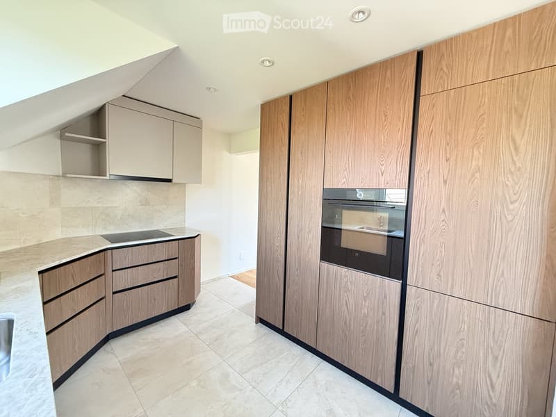Modern kitchen with light wood cabinets, stainless steel oven, and a sleek countertop.