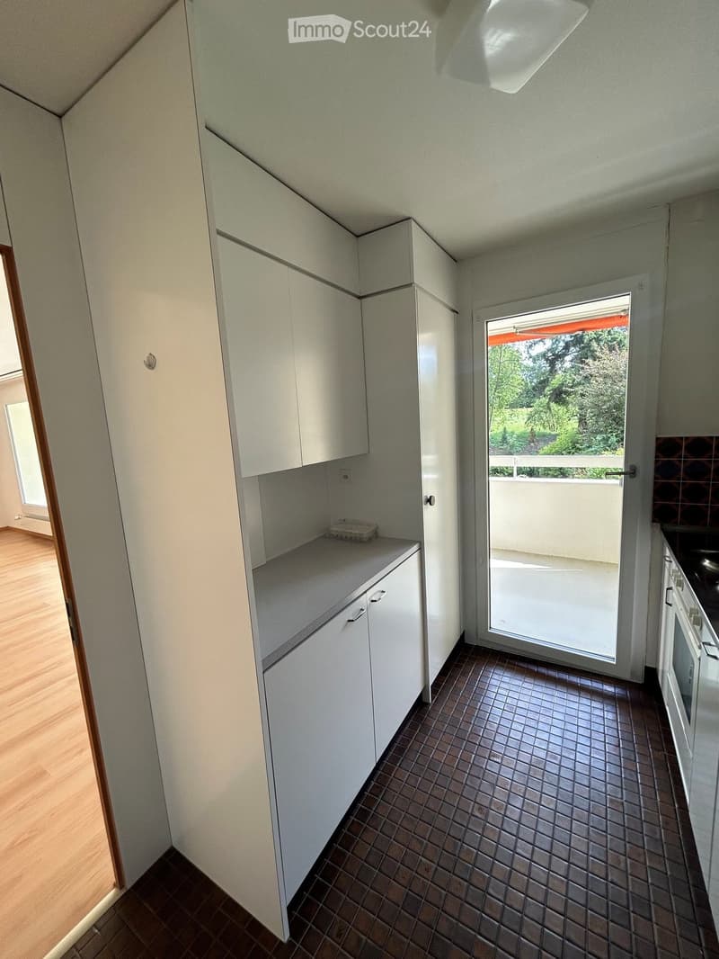 Modern kitchen with white cabinets, a tiled floor, and a sliding glass door leading to a balcony.