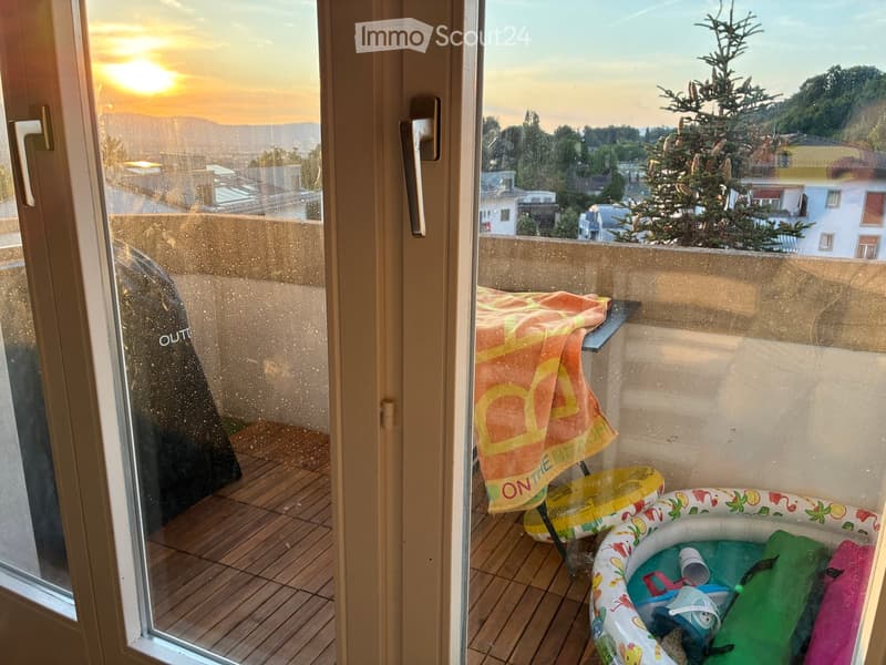 Balcony with wooden decking, towel, inflatable pool, and toys.