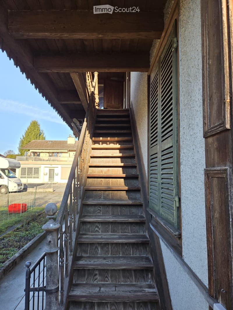 Wooden staircase leading up to a building entrance, with a metal railing and wooden steps.