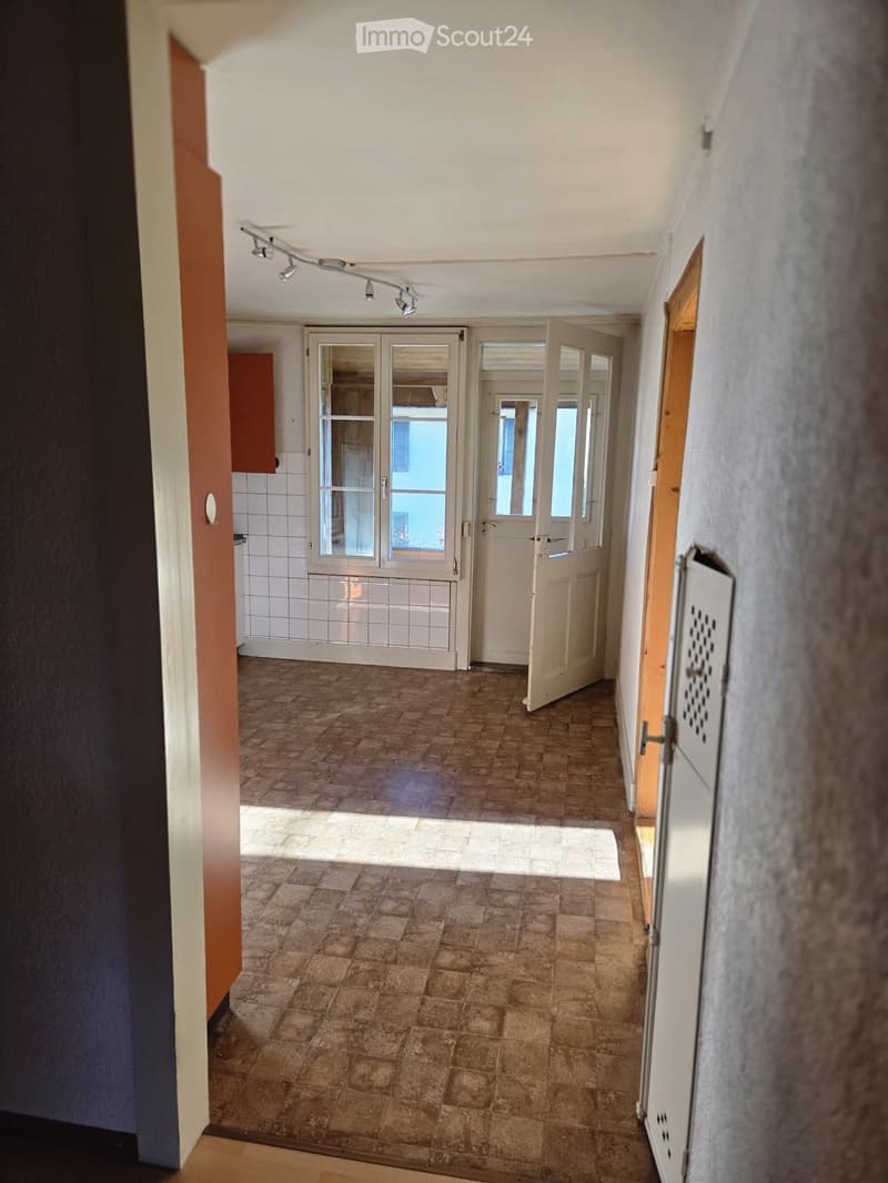Empty hallway with tiled floor, white walls, and multiple doors leading to other rooms.