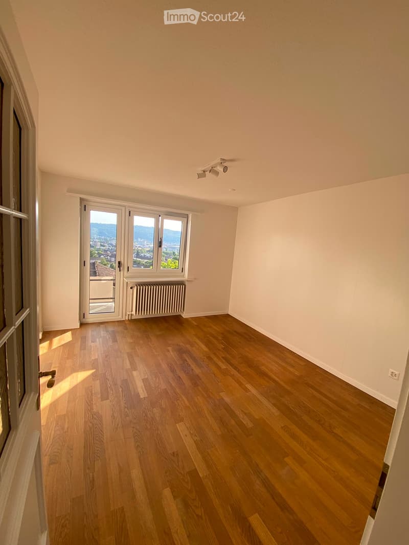 Empty room with wooden flooring, large windows, and a radiator. No furniture or equipment present.