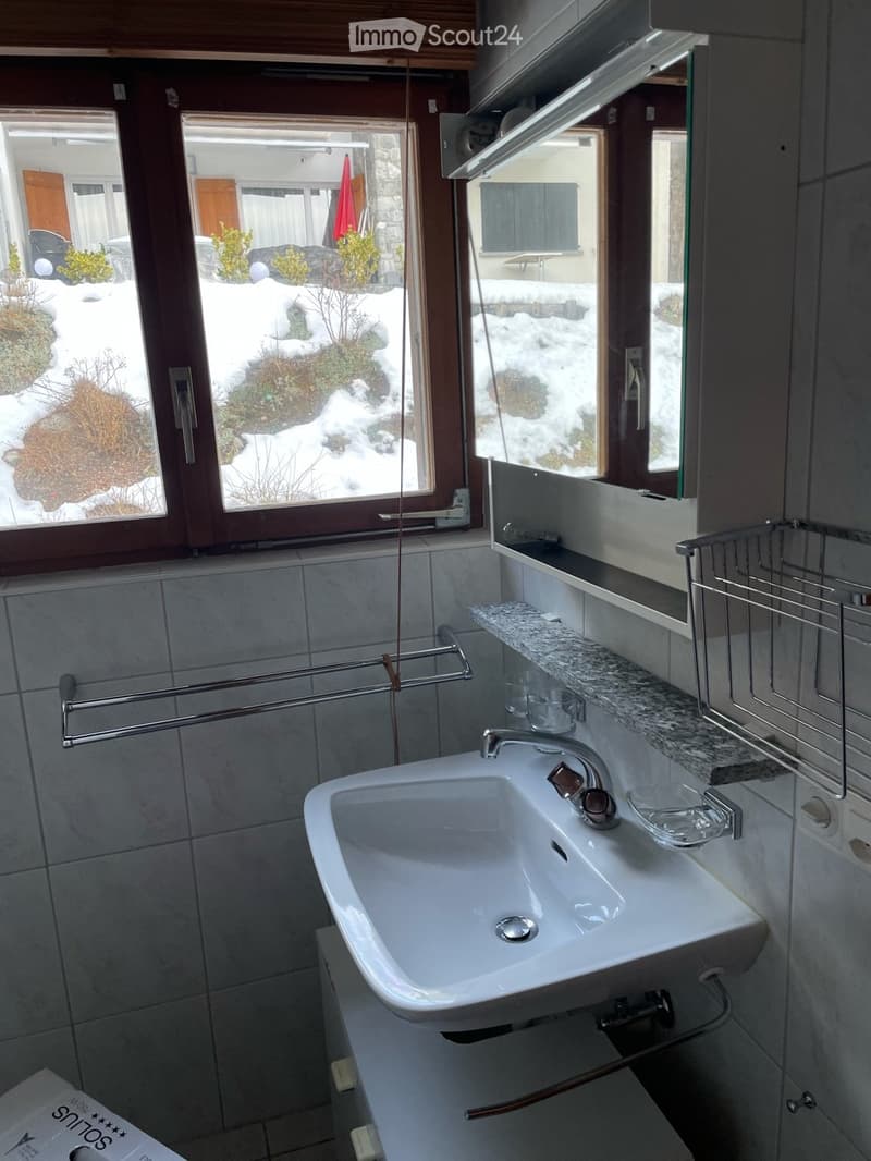 Bathroom with white sink, mirror, and tiled walls, window with snowy view outside