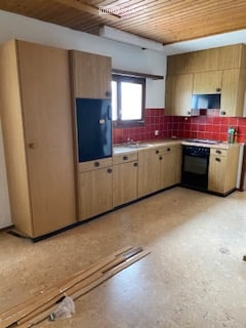 Modern kitchen with wooden cabinets, stainless steel appliances, and red brick backsplash. The space is unfurnished and appears to be under renovation.
