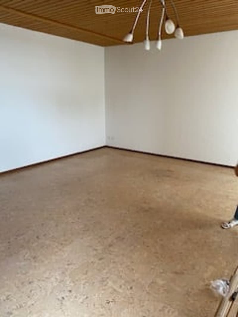 Empty room with white walls, wooden ceiling, and light brown carpeted floor. No furniture or equipment visible.