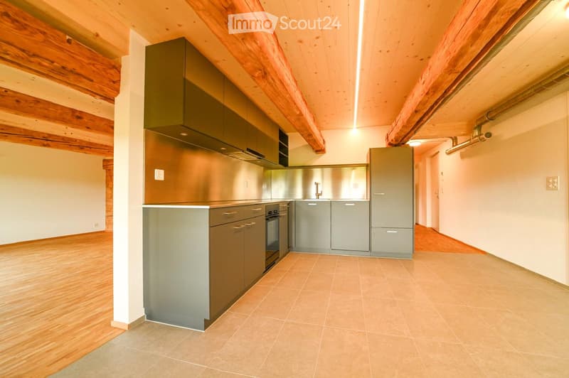 Modern kitchen with grey cabinets, stainless steel appliances, and wooden beams on the ceiling.