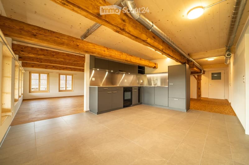 Modern kitchen with stainless steel appliances, wooden beams, and large windows.