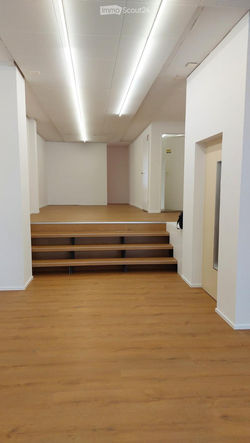 Empty hallway with wooden flooring, white walls, and a staircase leading upwards. No furniture or equipment present.