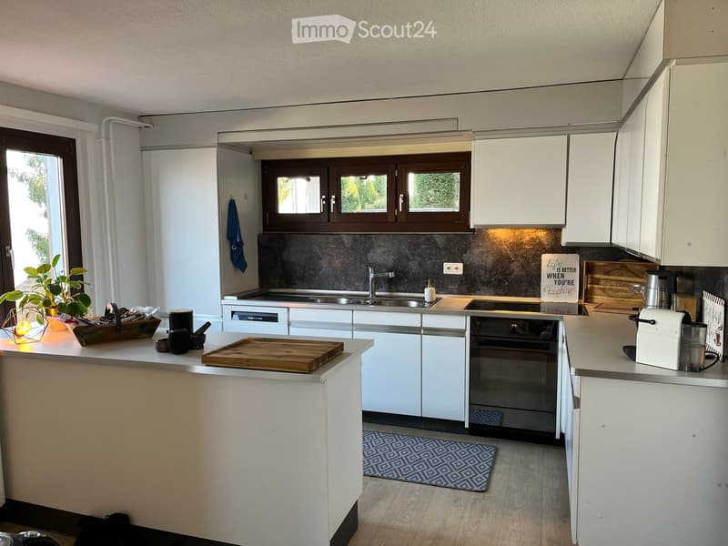 Modern kitchen with white cabinets, stainless steel appliances, island, and various kitchen items on the counter.