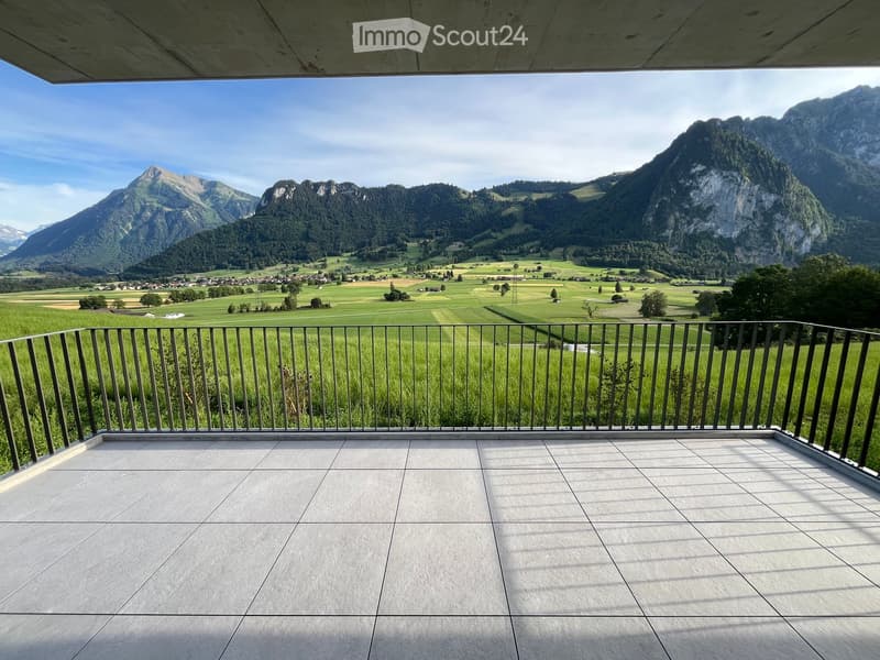 Modern balcony with a metal railing, tiled floor, and panoramic mountain view.