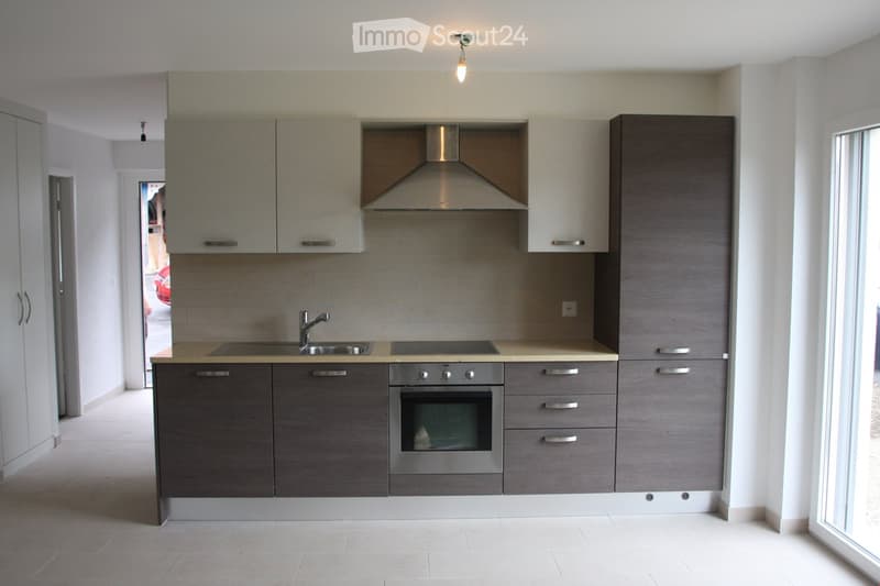 Modern kitchen with grey cabinets, stainless steel appliances, and a central island with a sink and stove.