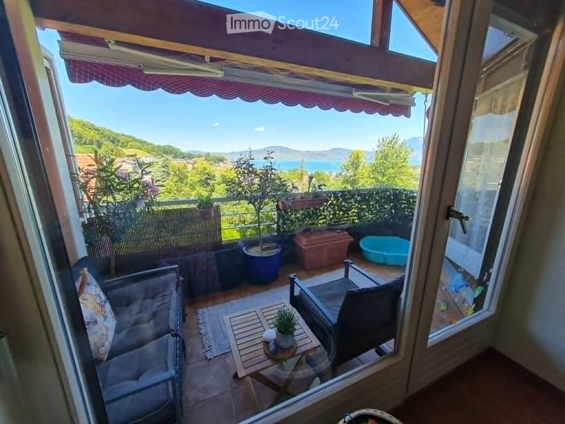Balcony with outdoor furniture, potted plants, and scenic view of the lake and mountains.