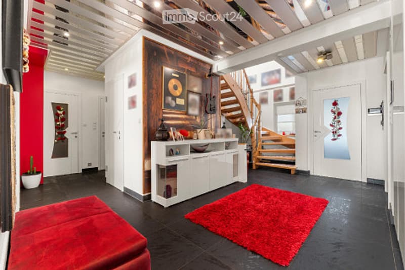 Modern living room with a red carpet, white cabinet, staircase, and decorative wall art.
