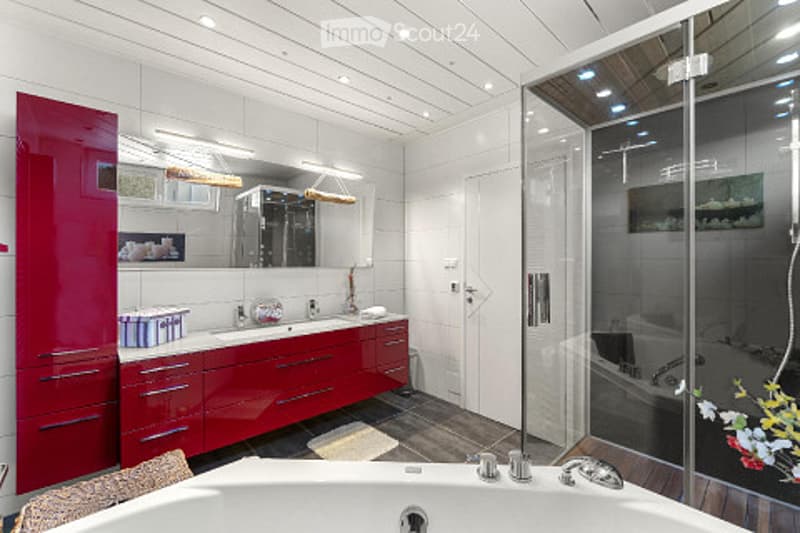 Modern bathroom with white tiles, red cabinetry, a large mirror, a bathtub, and a glass-enclosed shower stall.