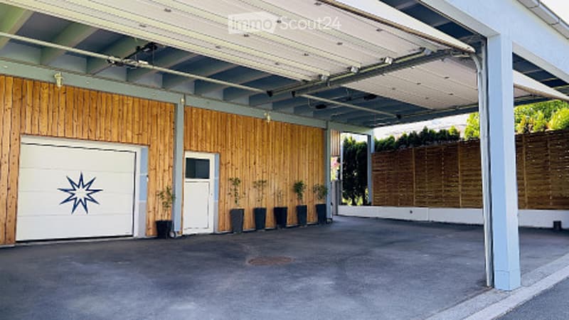 Modern garage with wooden paneling, white garage door, and small potted plants lining the entrance.