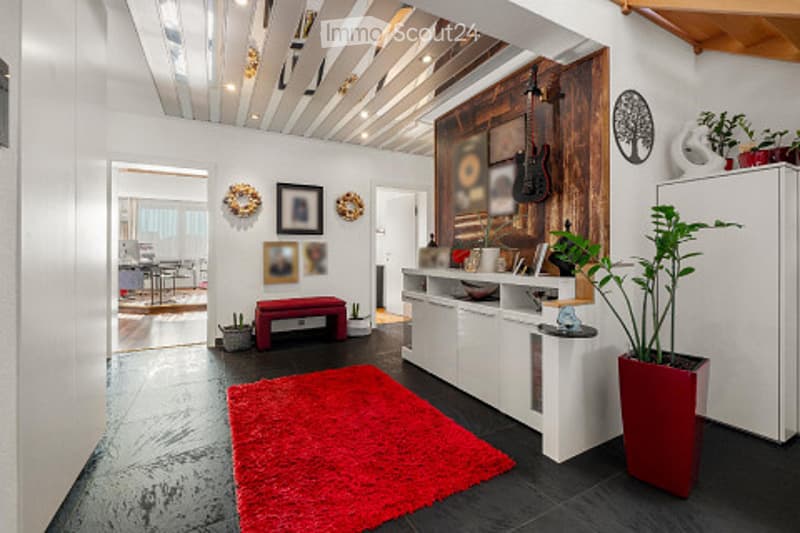 Modern living room with white walls, dark flooring, red shag rug, white cabinetry, and decorative artwork.