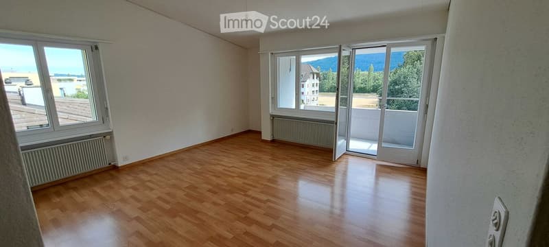 Empty room with wooden flooring, large windows, and a view of the landscape.