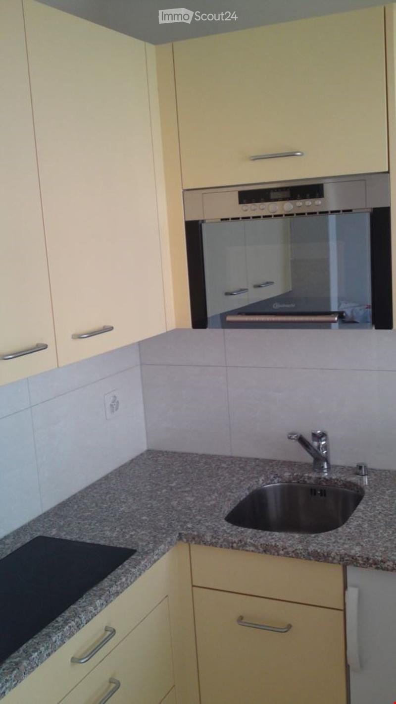 Modern kitchen with light-colored cabinets, granite countertop, stainless steel sink and faucet, and built-in oven.