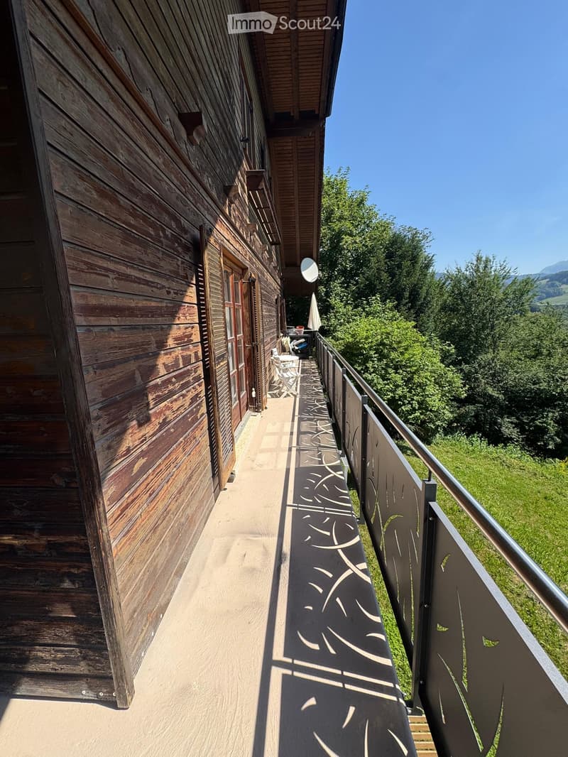 Balcony with wooden walls, metal railing, and scenic mountain view.