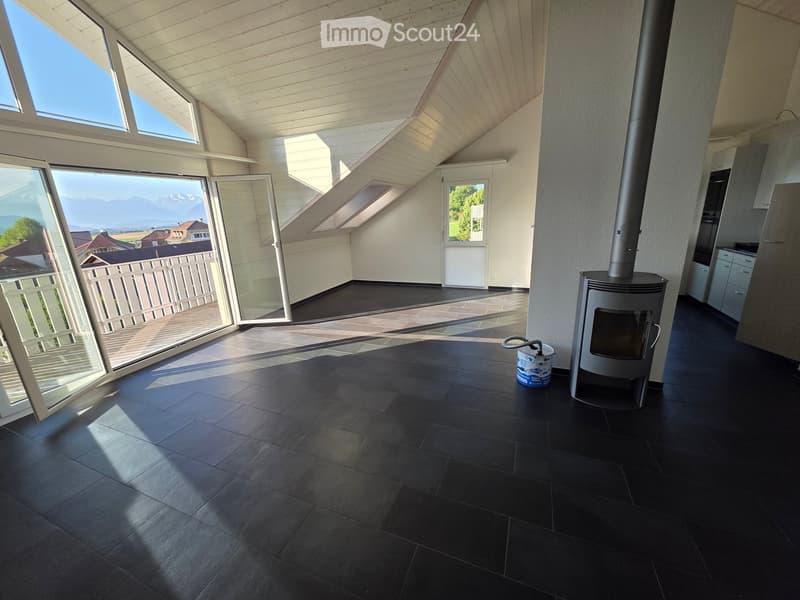 Modern room with dark tiled floor, fireplace, large windows offering a scenic view, and a small bucket near the fireplace.
