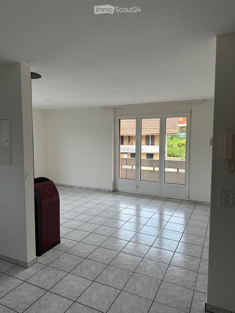 Empty room with tiled floor, white walls, and a large sliding glass door leading to a balcony or outdoor area.