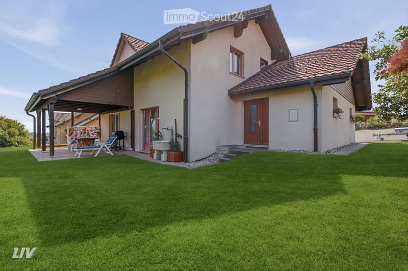 Two-story house with beige walls, red-tiled roof, and a covered patio area with outdoor furniture.