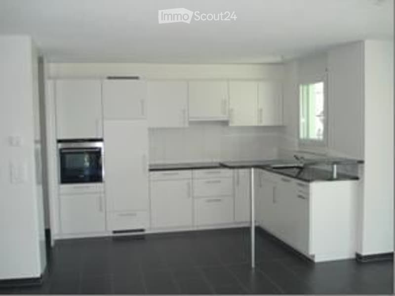Bright, modern kitchen with white cabinets, stainless steel appliances, and black tiled flooring.