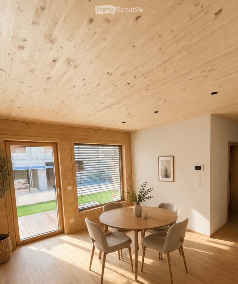 Bright dining area with wooden ceiling and walls, large windows, and a round wooden dining table with six chairs.