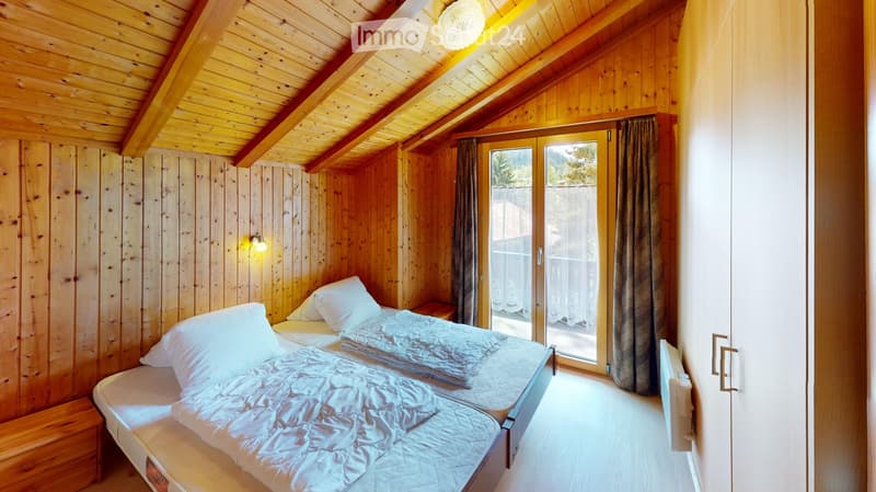 Cozy wooden bedroom with two single beds, nightstand, and large window with curtains.