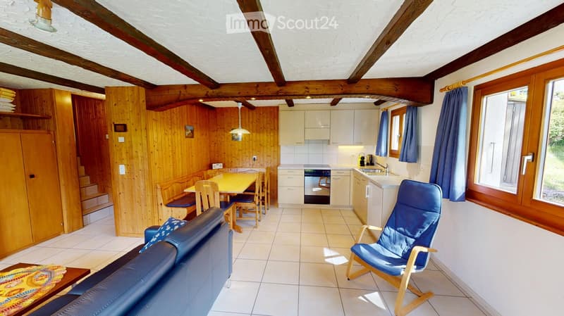 Cozy living and dining area with a sofa, armchair, dining table, and kitchen area featuring cabinets, a dishwasher, and a sink.
