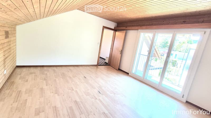 Empty room with wooden flooring, white walls, and large sliding glass doors leading to a balcony and pool area.