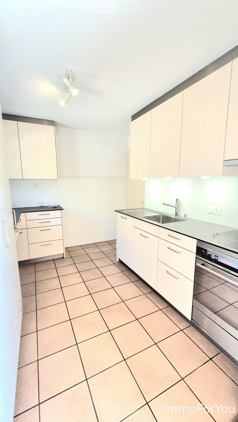 Modern kitchen with white cabinets, tiled floor, sink, faucet, and built-in oven.