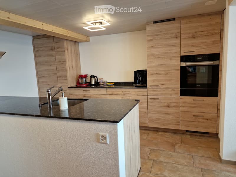 Modern kitchen with wooden cabinets, granite countertop, stainless steel sink, and various appliances including a coffee maker and mixer.