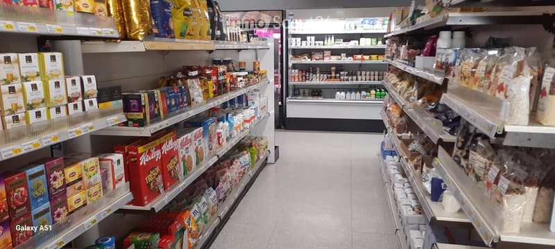 A grocery store aisle with shelves stocked with various food products, including cereals, teas, and packaged goods.