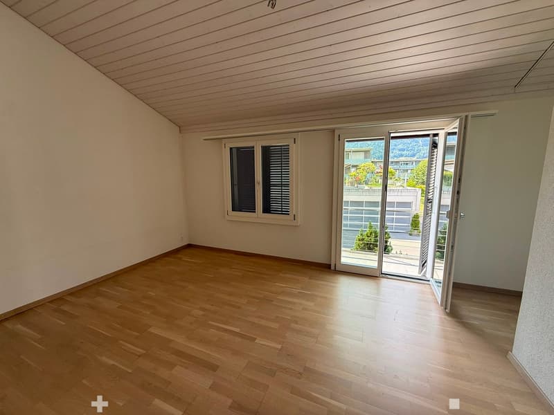 Empty room with wooden flooring, white walls, and large sliding glass doors leading to a balcony or outdoor area.
