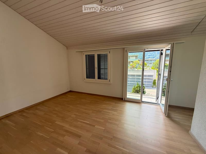 Empty room with wooden flooring, white walls, and large sliding glass doors leading to a balcony or outdoor area.