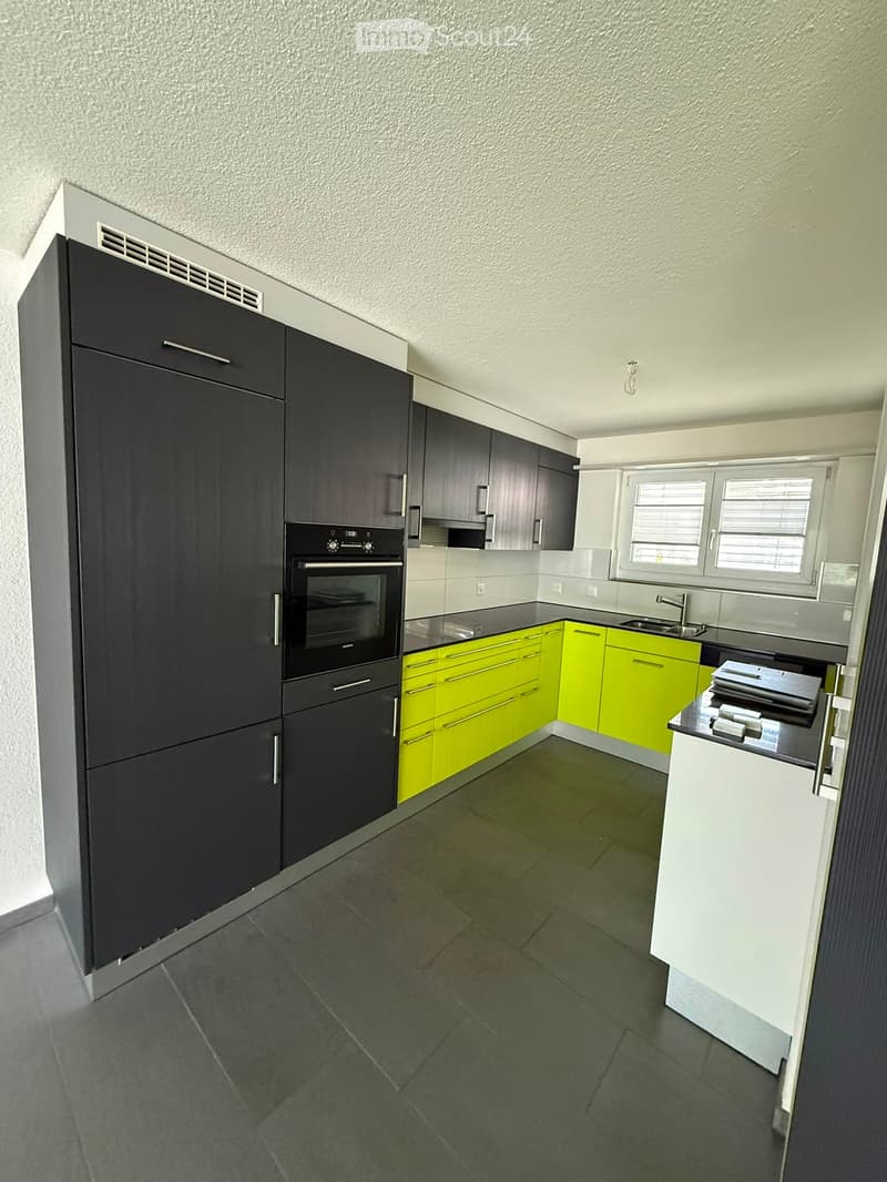 Modern kitchen with dark grey and bright yellow cabinets, an oven, a sink with a faucet, and tiled flooring.