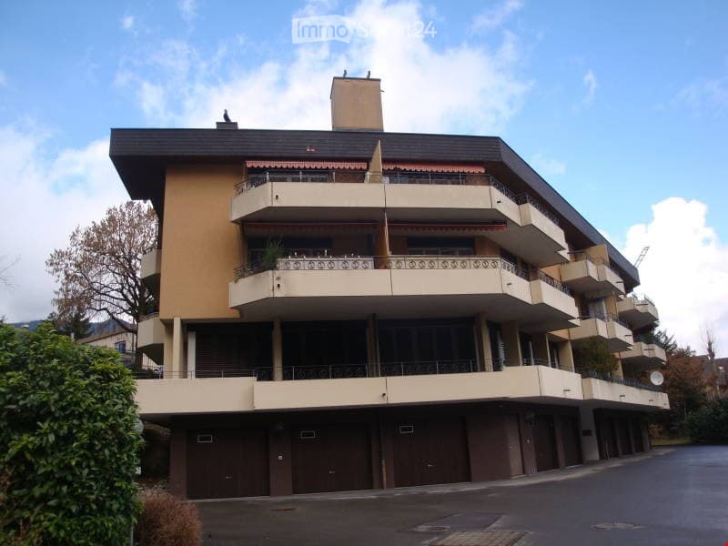 Multi-story residential building with balconies and a garage area.