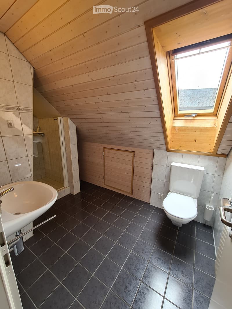 Modern bathroom with wooden walls, dark tiled floor, toilet, sink, bathtub, and shower area.