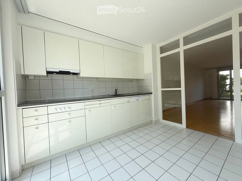 Modern kitchen with white cabinets, tiled walls, and a granite countertop. Features a sink, faucet, and an oven.