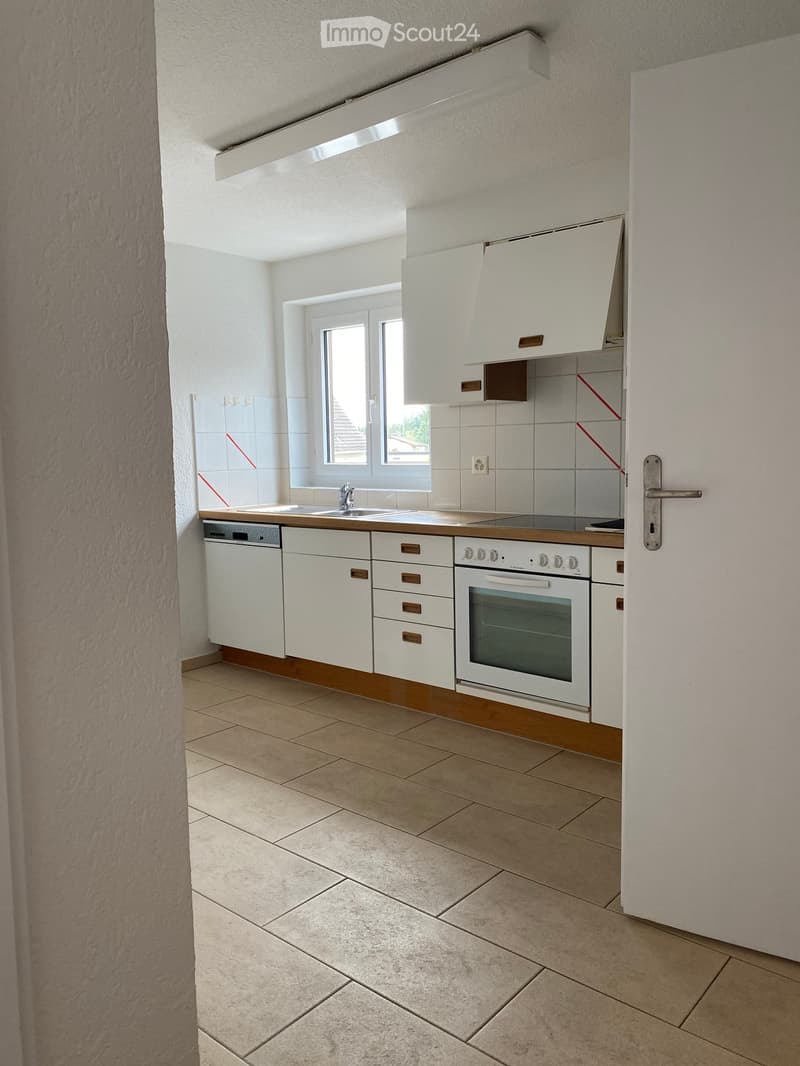 Modern kitchen with white cabinets, a sink, an oven, and a dishwasher. The space features tiled walls and a tiled floor.