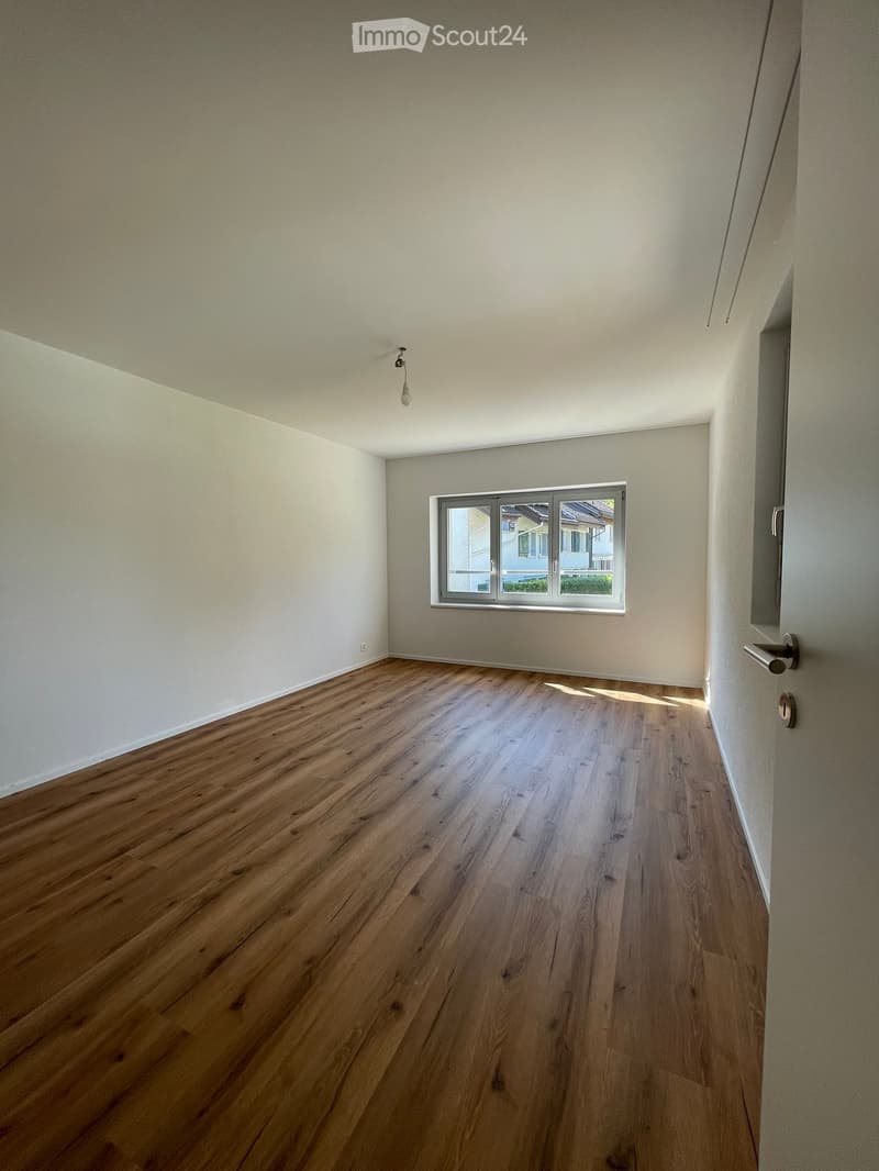 Empty room with wooden flooring, white walls, and a single window with a view of the outside.