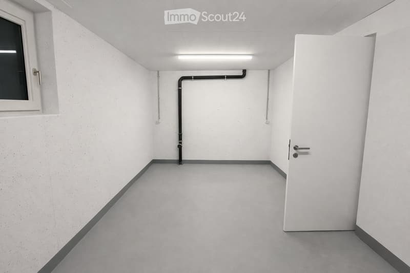 Empty room with white walls, grey floor, and a window on one side. No furniture or equipment is present.