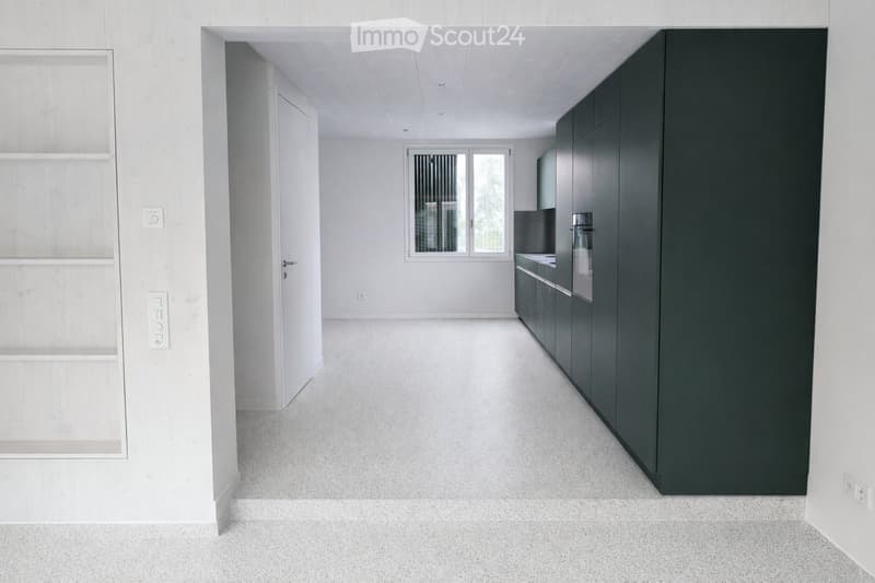 Empty room with white walls, grey cabinets, and a window with blinds. No furniture or equipment present.